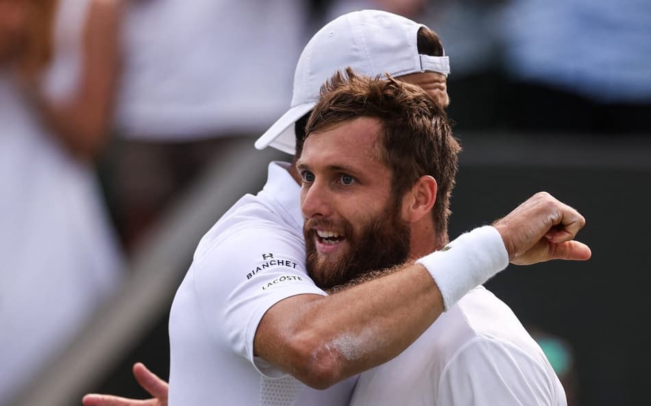O búlgaro Grigor Dimitrov (e) abraça o francês Corentin Moutet após a vitória em Wimbledon (Fto: HENRY NICHOLLS / AFP)