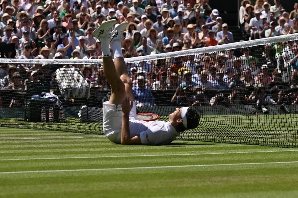 O americano Taylor Fritz escorrega na grama na partida contra o espanhol Carlos Alcaraz em Wimbledon (Foto: Glyn KIRK / AFP)