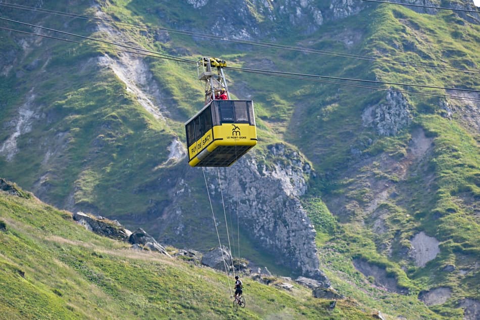 Um ciclista se pendura em uma gôndola na área de chegada no topo do Mont-Dore Puy de Sancy durante a 10ª etapa da Tour de France 2025 (foto: Loic VENANCE / AFP)