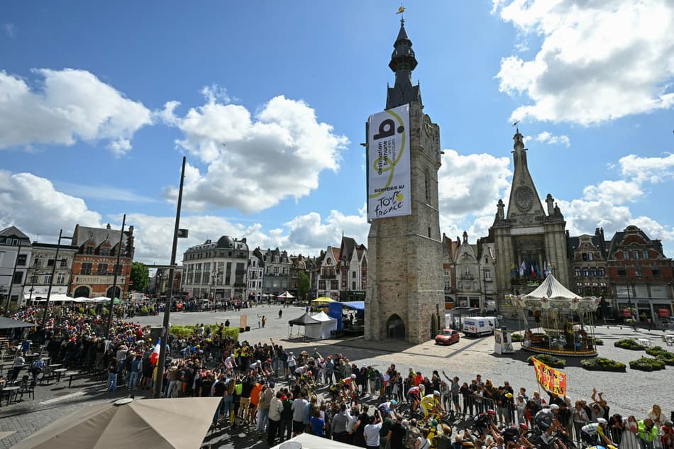 O grupo de ciclistas passa pelo Beffroi, na Grand' Place em Bethune (foto: Loic VENANCE / AFP)