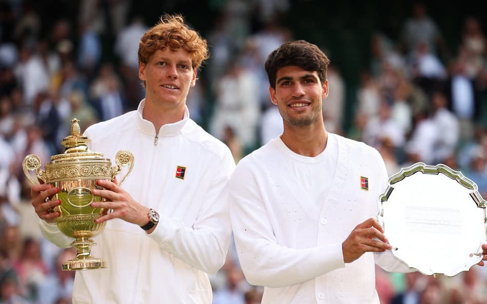 O italiano Jannik Sinner e o espanhol Carlos Alcaraz com os troféus de Wimbledon (Foto: HENRY NICHOLLS / AFP)