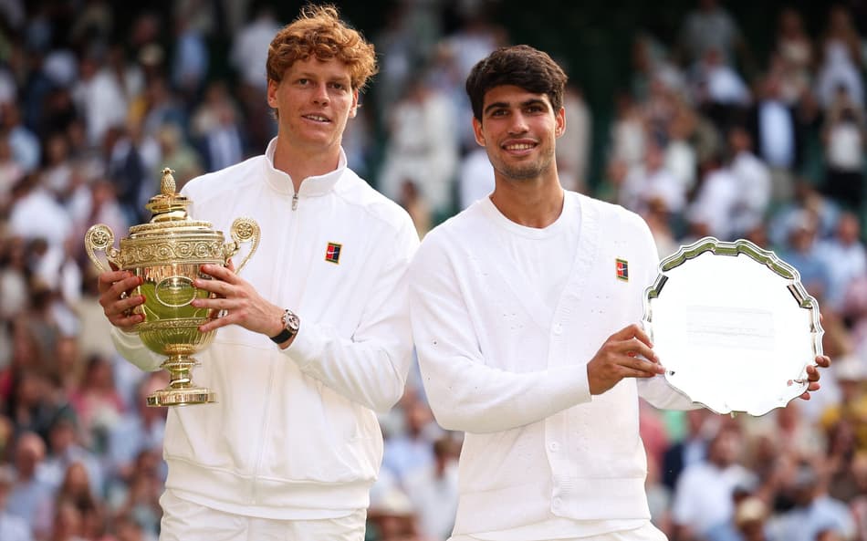 O italiano Jannik Sinner e o espanhol Carlos Alcaraz com os troféus de Wimbledon (Foto: HENRY NICHOLLS / AFP)