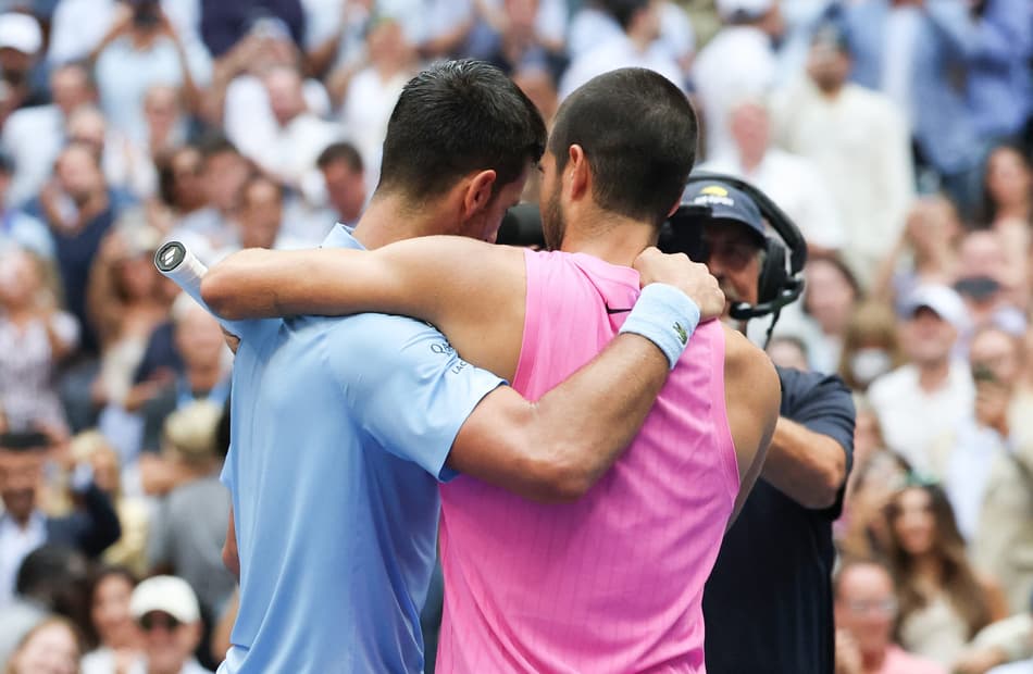 O espanhol Carlos Alcaraz (d) é abraçado pelo sérvio Novak Djokovic após a semifinal do US Open (Foto: TIMOTHY A. CLARY / AFP)