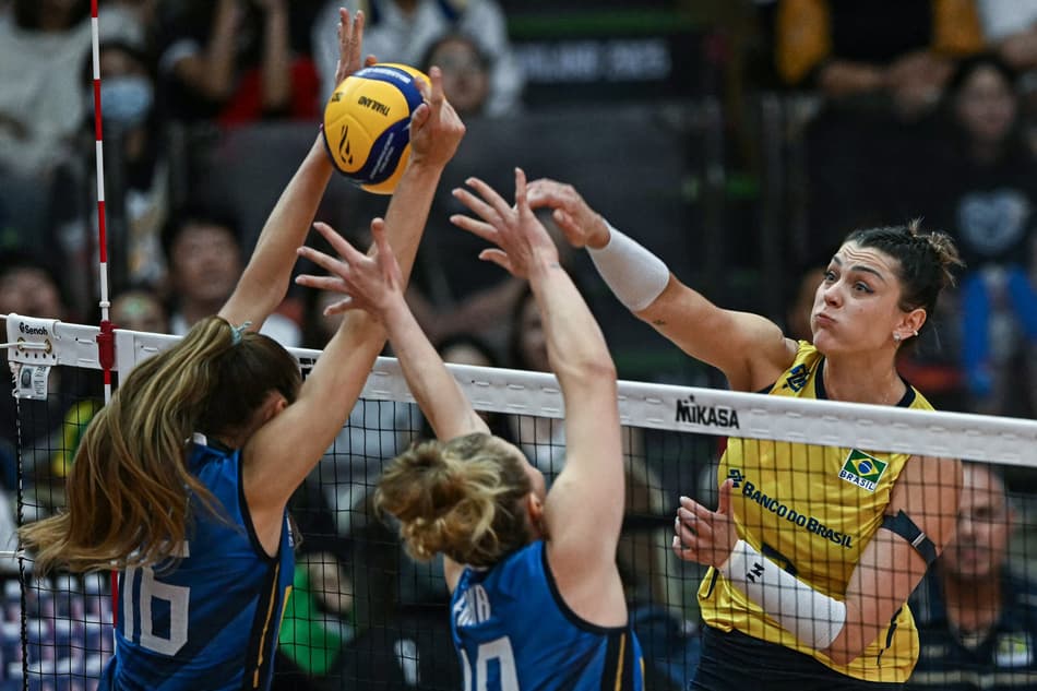 Brazil's #7 Rosamaria Montibeller (R) spikes the ball as Italy's #19 Sarah Luisa Fahr (C) and Italy's #16 Stella Nervini (L) attempt to block during their 2025 Women's Volleyball World Championships semi-final match in Bangkok on September 6, 2025. (Photo by Lillian SUWANRUMPHA / AFP)