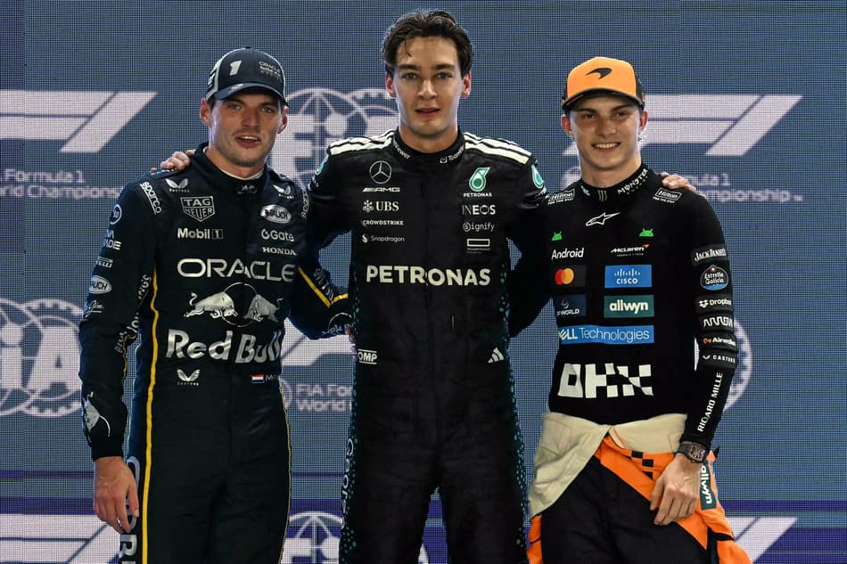 Mercedes' British driver George Russell (C) celebrates getting pole position with second placed Red Bull Racing's Dutch driver Max Verstappen (L) and third placed McLaren's Australian driver Oscar Piastri (R) after the qualifying session for the Formula One Singapore Grand Prix night race at the Marina Bay Street Circuit in Singapore on October 4, 2025. (Photo by MOHD RASFAN / AFP)