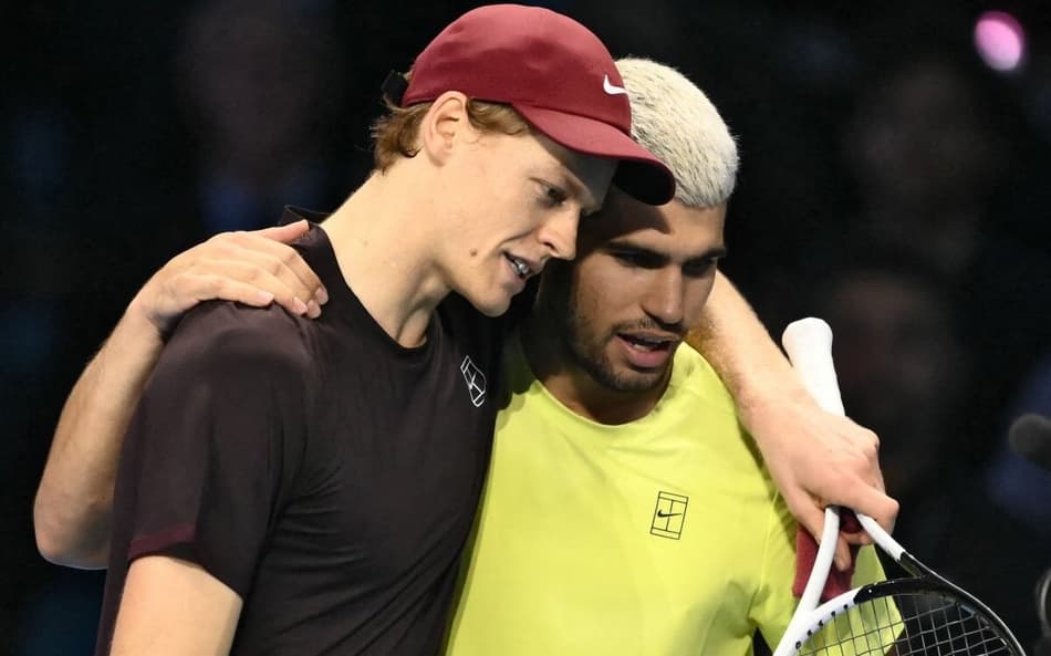 Italiano Jannik Sinner é abraçado pelo espanhol Carlos Alcaraz após a vitória na decisão do ATP Finals de Turim (Photo by Marco BERTORELLO / AFP)