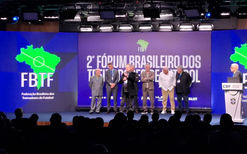 Oswaldo de Oliveira discursa em palco com Carlo Ancelotti