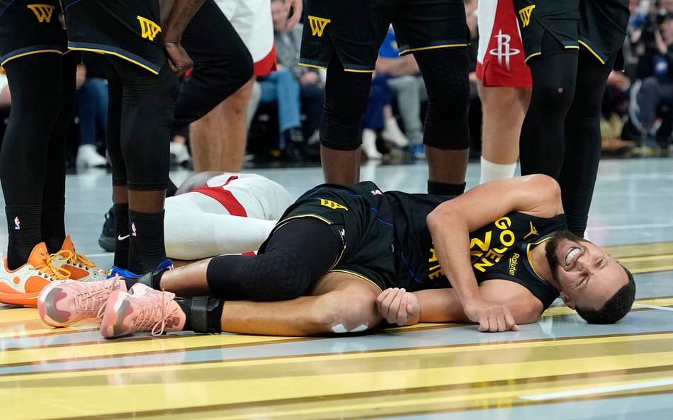 Stephen Curry deitado com dores em jogo entre Warriors e Rockets na NBA (Foto: Thearon W. Henderson/Getty Images/AFP)