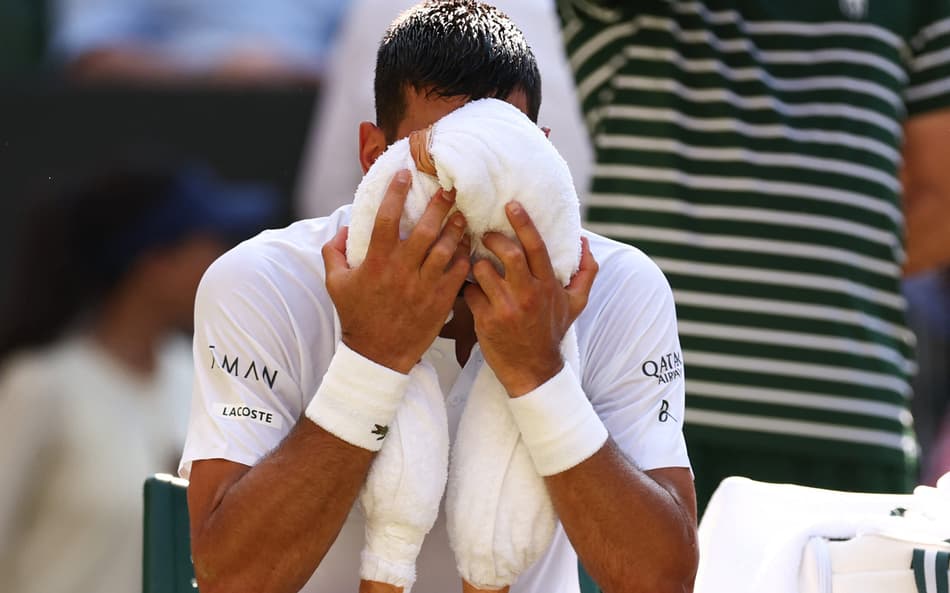 Novak Djokovic tenta aliviar o calor na partida contra o líder do ranking, Jannik Sinner (Foto: HENRY NICHOLLS / AFP)