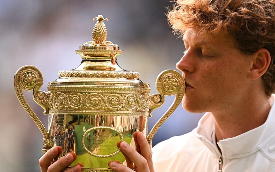 O italiano Jannik Sinner beija seu quarto Grand Slam, o primeiro em Wimbledon (Foto: Kirill KUDRYAVTSEV / AFP)