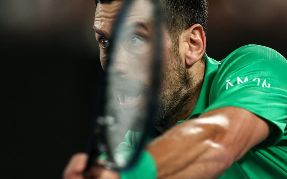O sérvio Novak Djokovic devolve a bola na partida contra o italiano Jannik Sinner na semifinal do Australian Open (Foto: IZHAR KHAN / AFP)