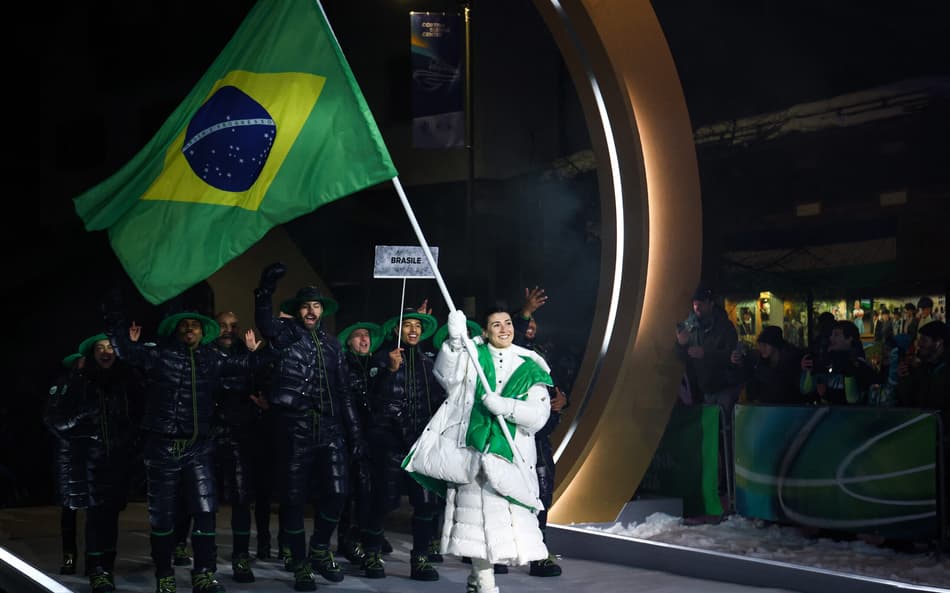 A porta-bandeira do Brasil, Nicole Rocha Silveira (D), desfila com a delegação na cerimônia de abertura dos Jogos Olímpicos de Inverno Milano Cortina 2026, em 6 de fevereiro de 2026. (Foto: Franck Fife/AFP)