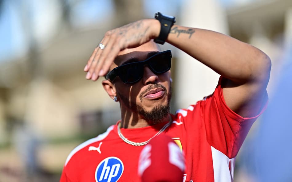 Lewis Hamilton, piloto britânico da Ferrari, protege o rosto do sol durante entrevista no primeiro dia de testes de pré-temporada da Fórmula 1 no Circuito Internacional do Bahrein, em Sakhir, em 11 de fevereiro de 2026. (Foto: Giuseppe Cacace/AFP)