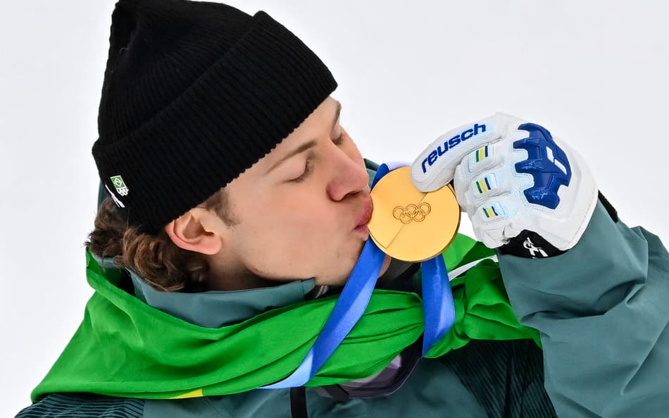 Lucas Pinheiro Braathen beija a medalha de ouro no pódio do slalom gigante masculino em 2026. (Foto: Fabrice Coffrini/AFP)