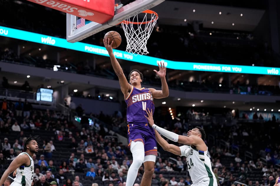 Oso Ighodaro, do Phoenix Suns, faz bandeja sobre Giannis Antetokounmpo, do Milwaukee Bucks, no Fiserv Forum, em Milwaukee (Foto: John Fisher/Getty Images/AFP).