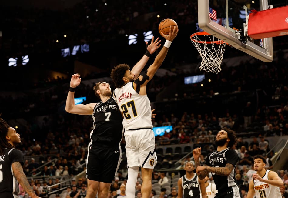 Jamal Murray, do Denver Nuggets, passa por Luke Kornet, do San Antonio Spurs, em jogo no Frost Bank Center, em San Antonio, em 12 de março de 2026 (Foto: Ronald Cortes/Getty Images/AFP)