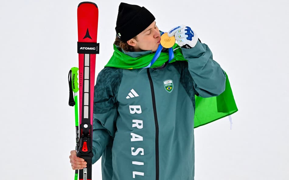 Lucas Pinheiro Braathen beija a medalha de ouro no pódio do slalom gigante masculino em 2026. (Foto: Fabrice Coffrini/AFP)