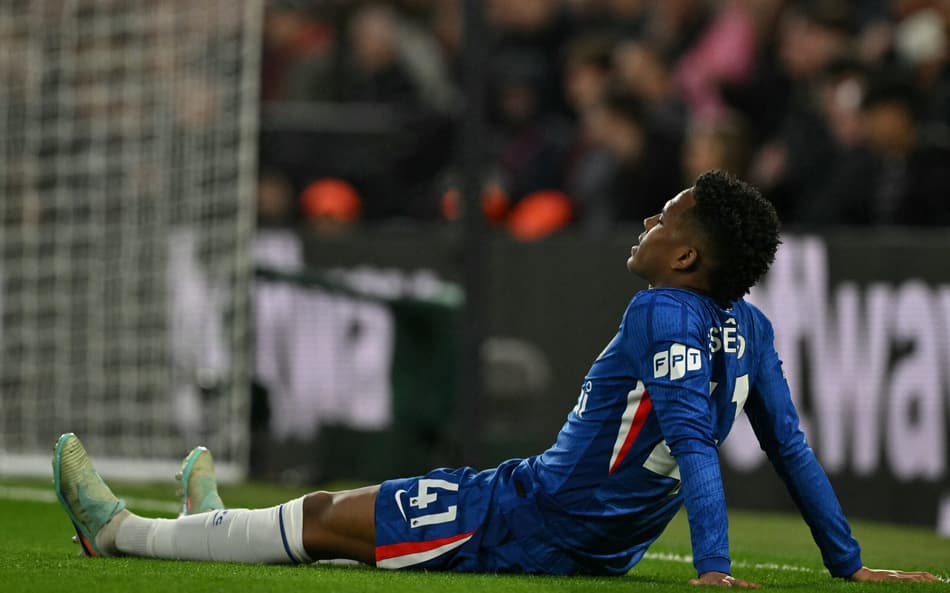 Estêvão caído no gramado após sentir lesão muscular na derrota do Chelsea para o Manchester United, na Premier League