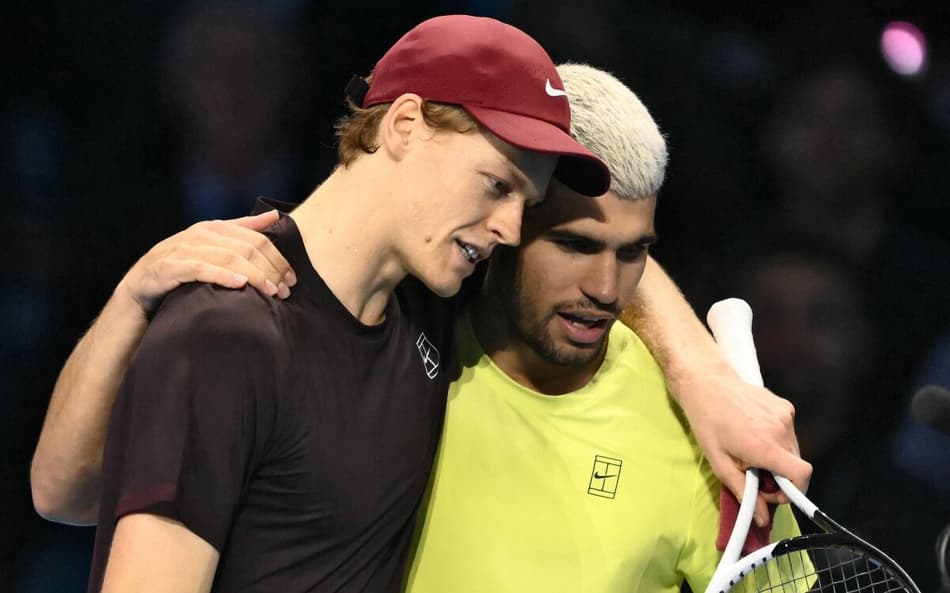 Italiano Jannik Sinner é abraçado pelo espanhol Carlos Alcaraz após a vitória na decisão do ATP Finals de Turim (Photo by Marco BERTORELLO / AFP)
