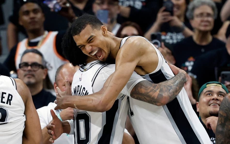 Victor Wembanyama e Julian Champagnie, do Spurs, se abraçam após vitória sobre o Trail Blazers no jogo cinco da primeira rodada dos playoffs da Conferência Oeste (Foto: Ronald cortes/Getty images/Afp)
