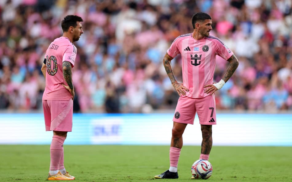 Messi e De Paul em campo com a bola no gramado