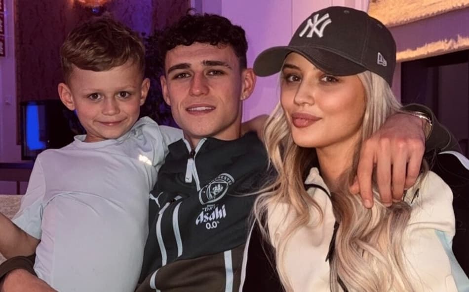 Phil Foden abraçado ao seu filho e a sua namorada, sorrindo