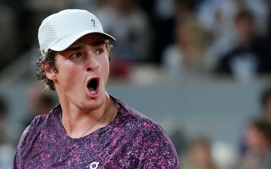 O brasileiro João Fonseca reage após um ponto em partida contra o tcheco Jakub Mensik pelas quartas de final de simples masculina no décimo dia do torneio de tênis de Roland Garros, na quadra Philippe-Chatrier, em Paris (Foto: Thomas Samson / Afp)
