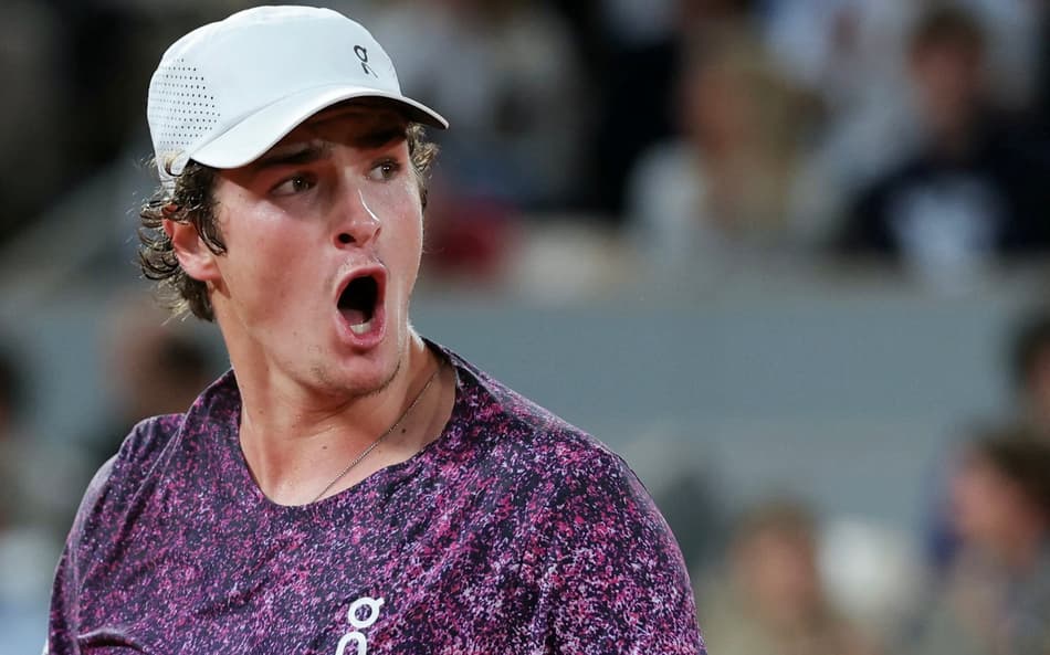 O brasileiro João Fonseca reage após um ponto em partida contra o tcheco Jakub Mensik pelas quartas de final de simples masculina no décimo dia do torneio de tênis de Roland Garros, na quadra Philippe-Chatrier, em Paris (Foto: Thomas Samson / Afp)