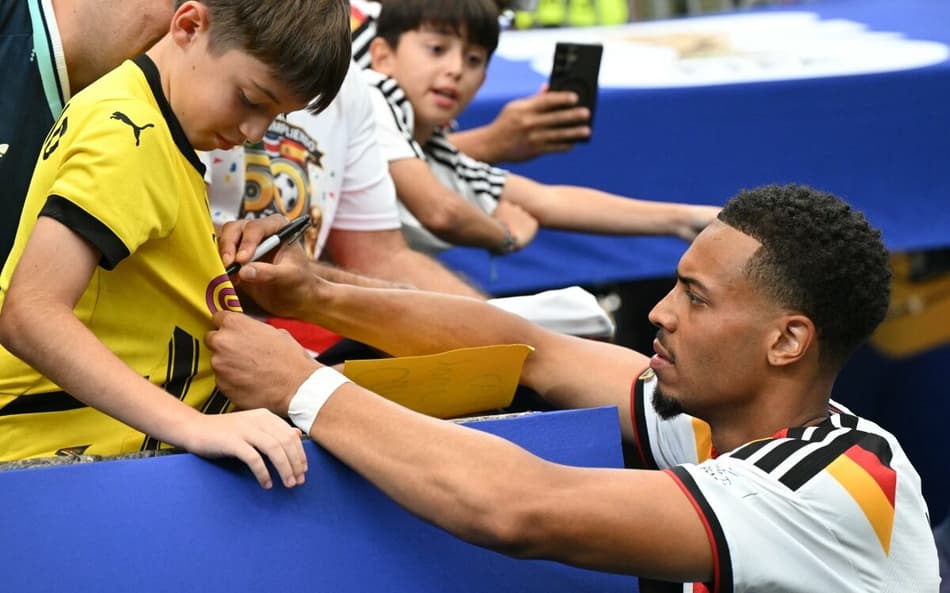 O meia alemão Felix Nmecha autografa a camisa de um pequeno fã em Houston (Foto: RONALDO SCHEMIDT / AFP)