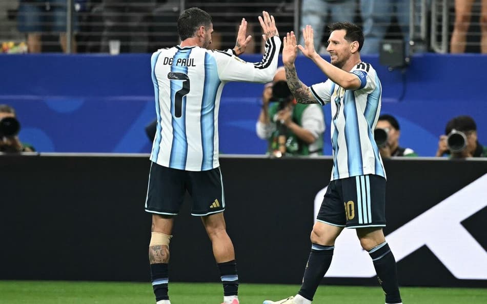 Lionel Messi comemora com De Paul seu primeiro gol na vitória sobre a Áustria (Foto: Paul ELLIS / AFP)