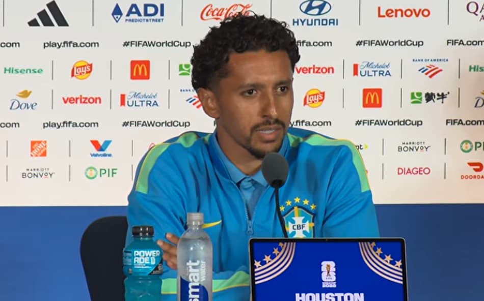 Marquinhos, capitão da Seleção Brasileira, fala ao microfone durante entrevista coletiva, ao lado de bola da Copa do Mundo