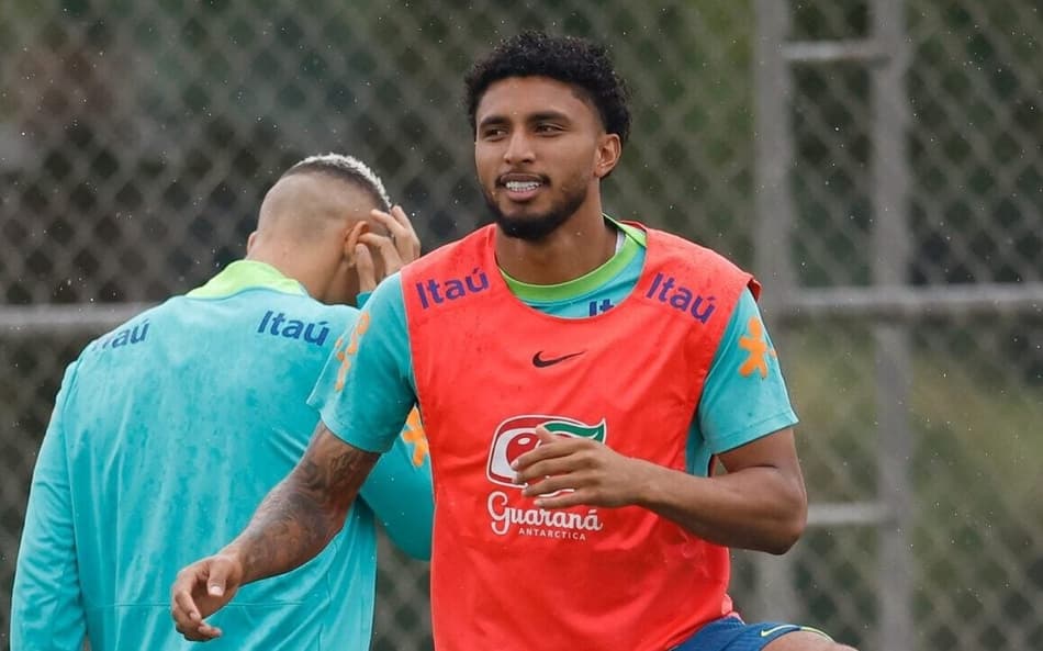 o volante Éderson se aquecendo com o colete laranja e uniforme verde de treino da seleção brasileira