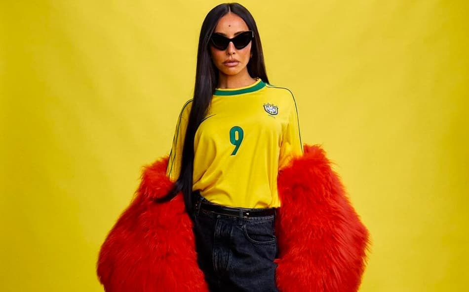 Sabrina Santo de camisa do Brasil, calça jeans e casaco vermelho
