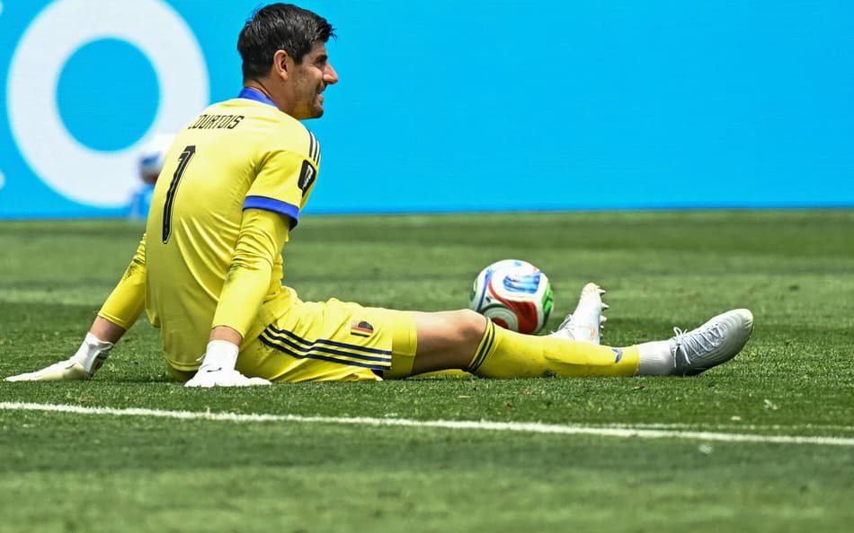 Courtois sentado em campo de uniforme amarelo