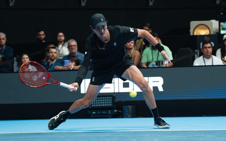 João Fonseca se agacha para devolver a bola para o australiano Nick Kyrgios