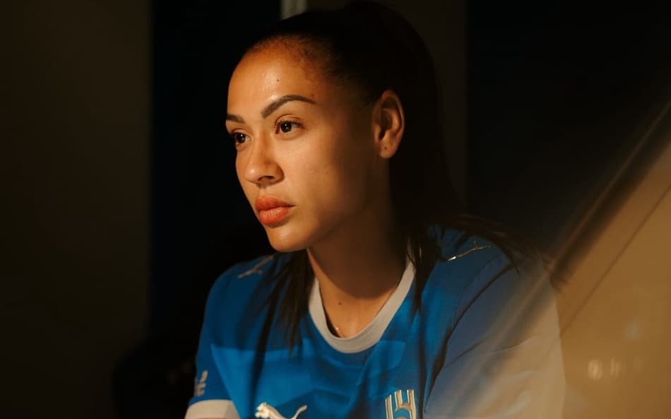 Kathellen Souza sentada olhando para frente com camisa do Al-Hilal durante apresentação