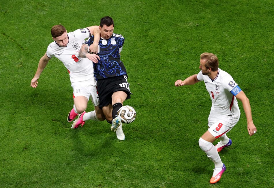O atacante #09 da Inglaterra, Harry Kane, observa enquanto o atacante argentino #10 Lionel Messi e o meio-campista inglês #08 Elliot Anderson disputam a bola durante a semifinal do torneio da Copa do Mundo de 2026 entre Inglaterra e Argentina