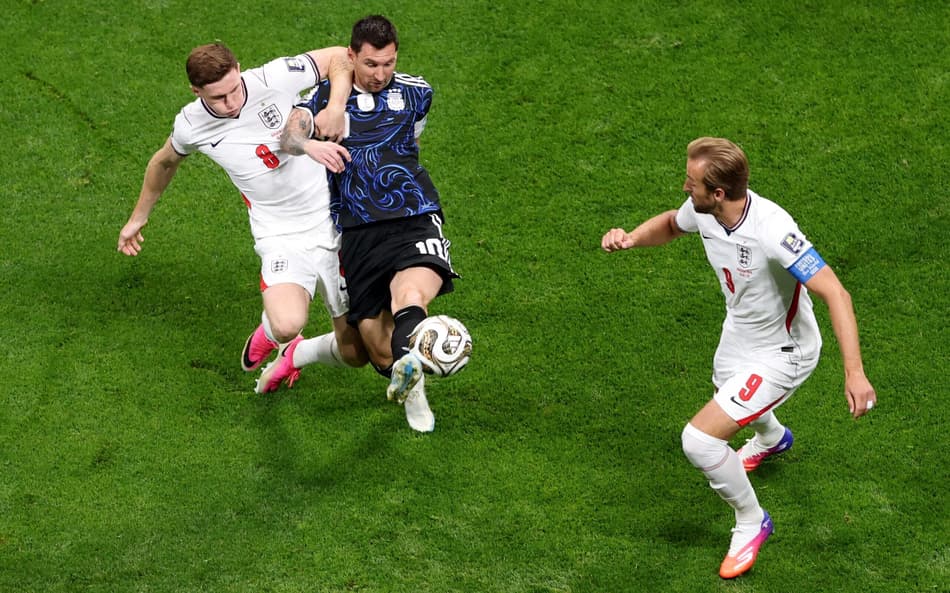 O atacante #09 da Inglaterra, Harry Kane, observa enquanto o atacante argentino #10 Lionel Messi e o meio-campista inglês #08 Elliot Anderson disputam a bola durante a semifinal do torneio da Copa do Mundo de 2026 entre Inglaterra e Argentina
