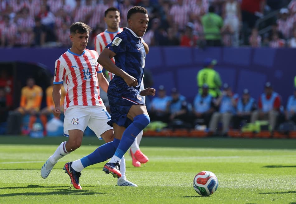 O atacante francês #10 Kylian Mbappé (R) corre com a bola além do meio-campista paraguaio #14 Andrés Cubas durante a partida das oitavas de final da Copa do Mundo de 2026 entre Paraguai e França