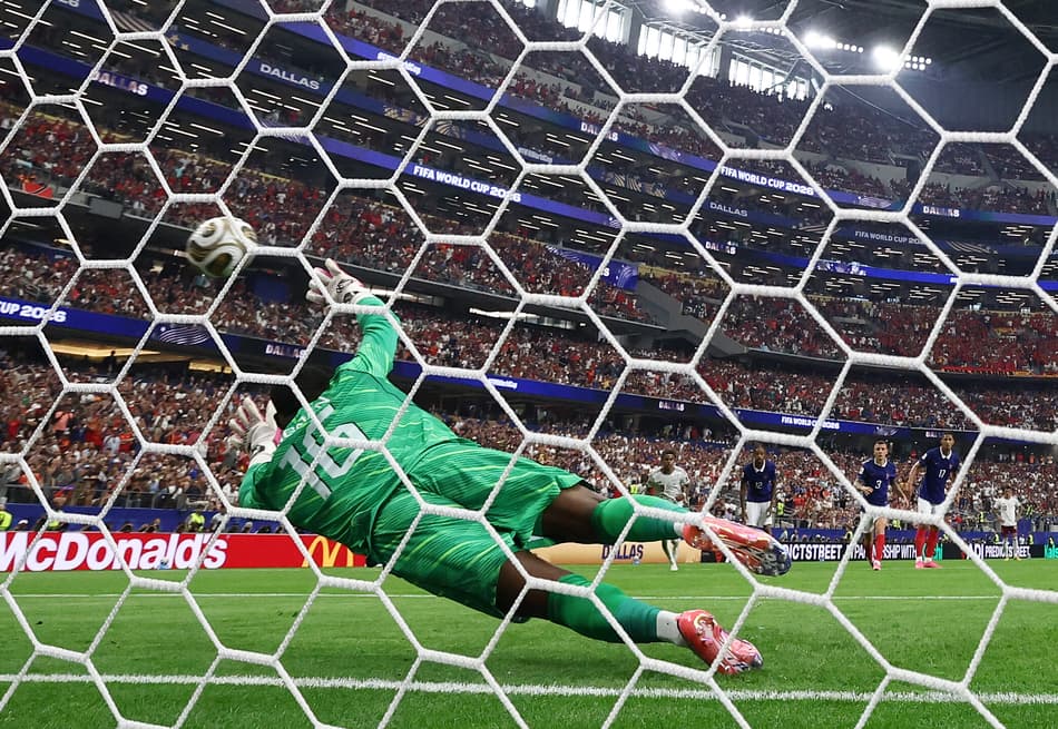 O goleiro francês #16 Mike Maignan sofre um gol no pênalti convertido pelo atacante espanhol #21 Mikel Oyarzabal (fora de quadro) e o primeiro gol de sua equipe durante a semifinal do torneio da Copa do Mundo de 2026 entre França e Espanha