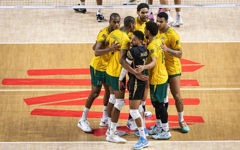 De camisas amarelas e shorts verdes, jogadores do Brasil se reúnem na quadra após marcarem ponto contra a França na VNL 2026