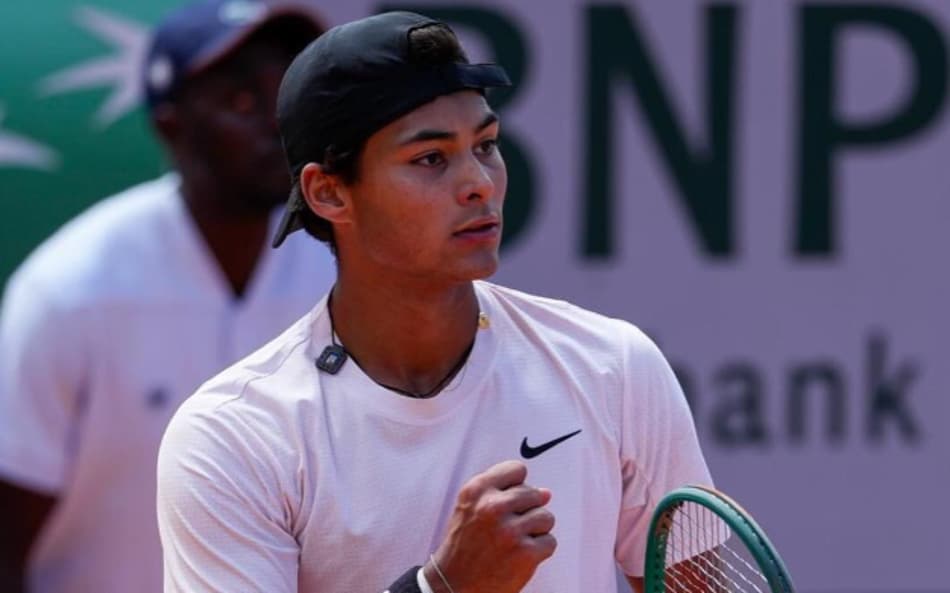 De camisa branca e boné preto, Guto Miguel cerra o punho e comemora ponto em jogo de Roland Garros