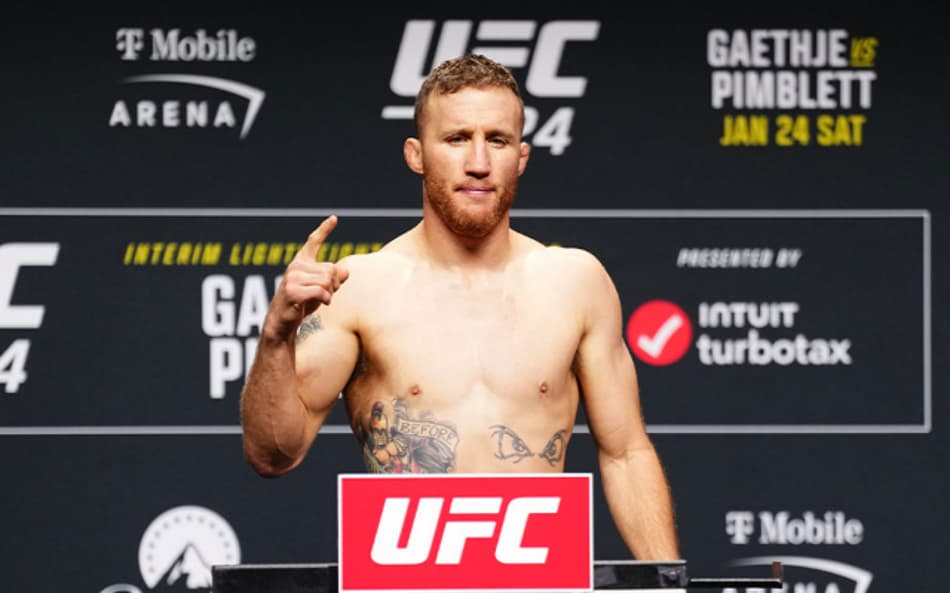 Em frente ao banner de patrocinadores do UFC, Justin Gaethje leva o dedo indicador direito durante o evento de pesagem