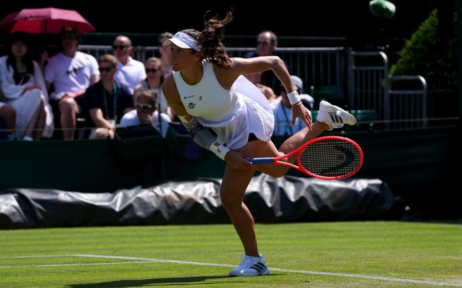 Com a perna direita no chão e a esquerda no ar, Luisa Stefani conclui movimento de saque em jogo de Wimbledon