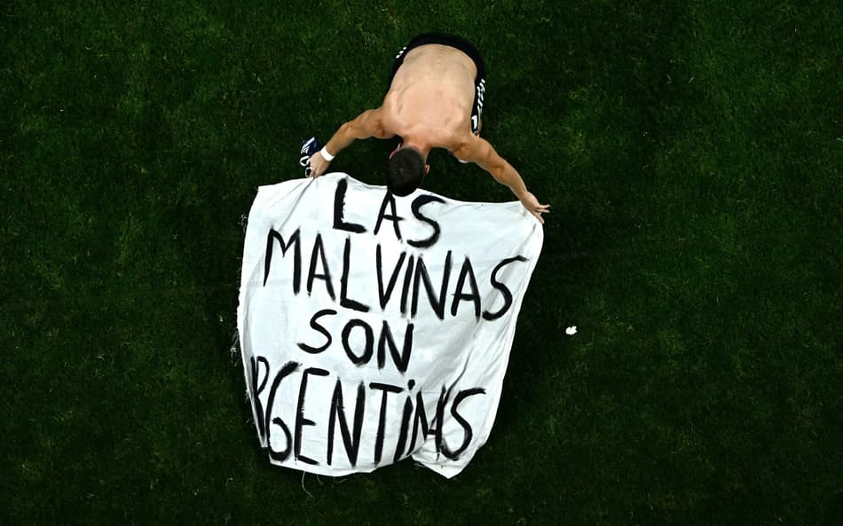 Giovani Lo Celso ajusta uma faixa com os dizeres "As Malvinas (Ilhas Falkland) pertencem à Argentina"