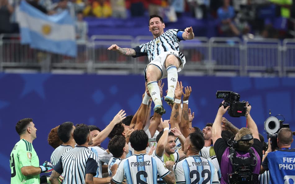 Messi sorridente é levantado por companheiros de time após vitória de virada da Argentina (Foto: Odd ANDERSEN / AFP)