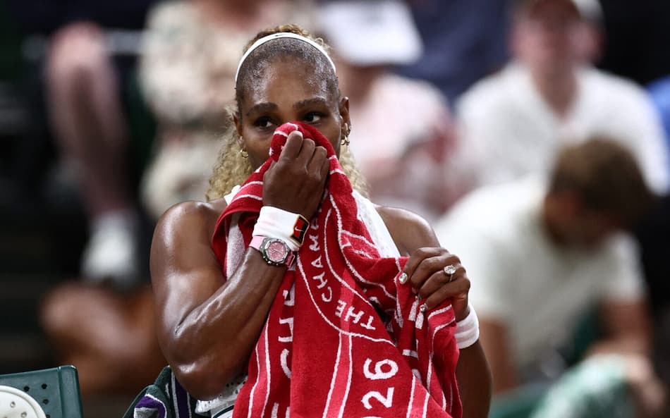 Sentada, Serena Williams seca o suor com uma toalha vermelha