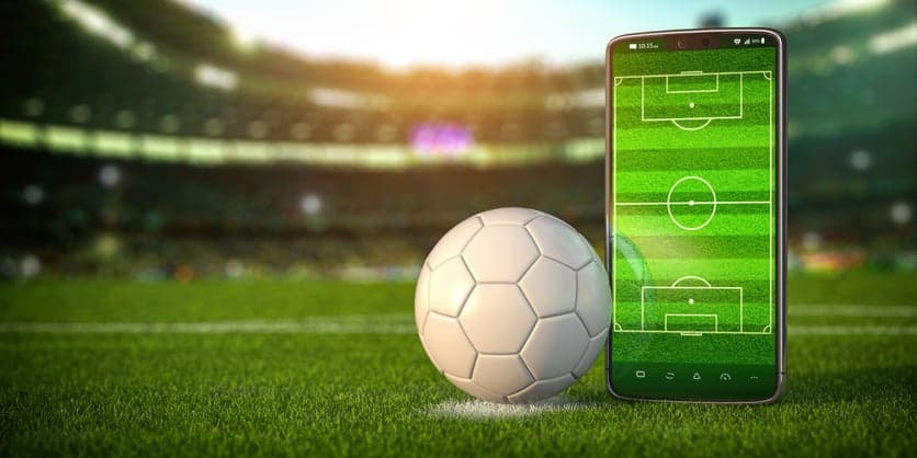Football app video game on smartphone and betting sport online concept. Mobile phone and soccer ball.